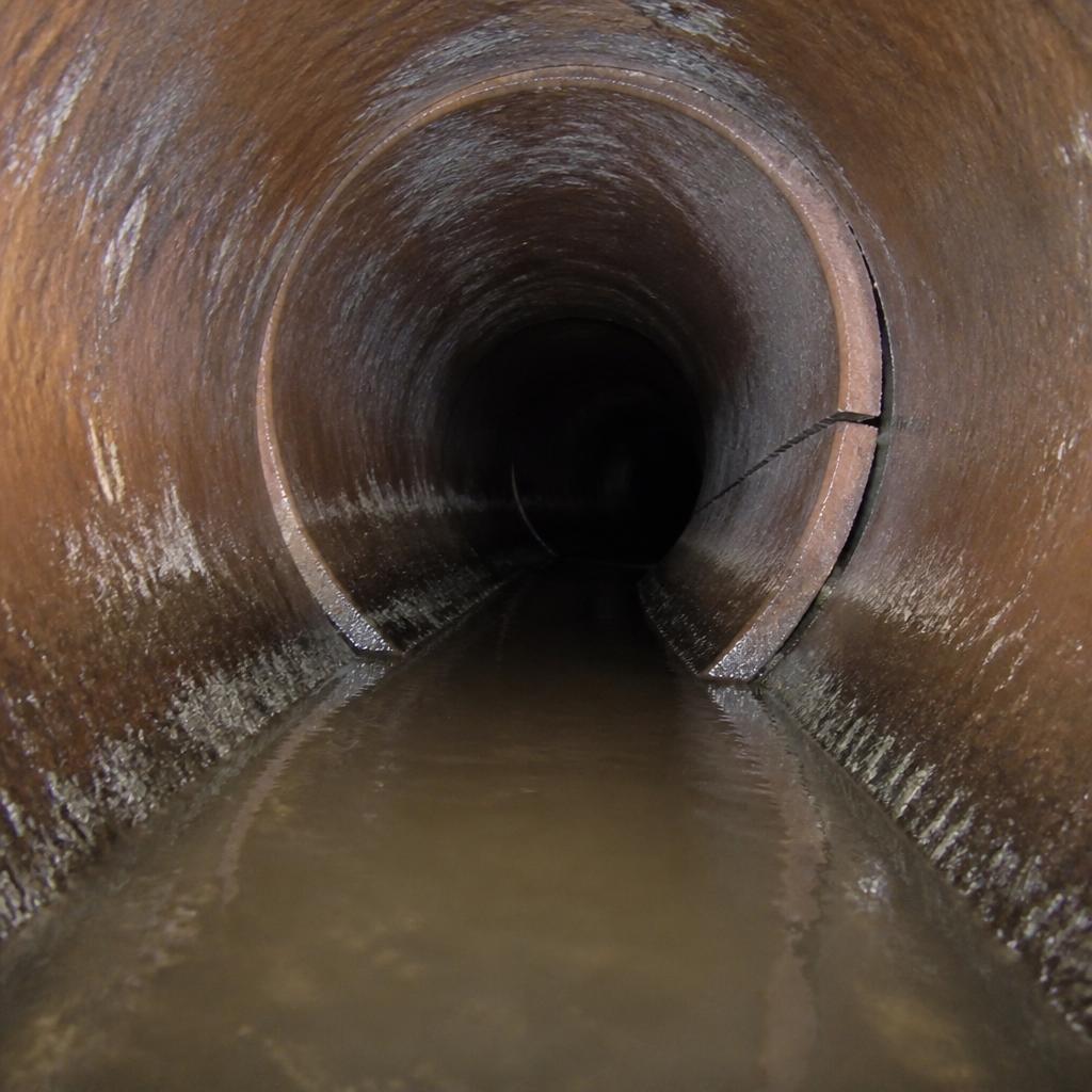 Sewer camera inspection still from a Round Rock flex building showing a cracked and offset pipe joint flagged with PACP defect codes