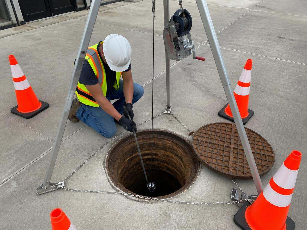 CSC Pipe Inspection technician running a NASSCO MACP manhole inspection at a Bertram commercial property near Highway 29 corridor, tripod and cones staged over the open structure